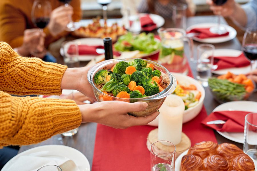 Woman-holding-bowl-of-vegetables-during-holiday-dinner