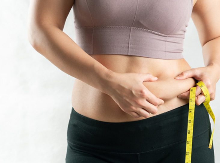 Woman-holding-excess-belly-fat-on-journey-to-weight-loss-after-endoscopic-sleeve-gastroplasty